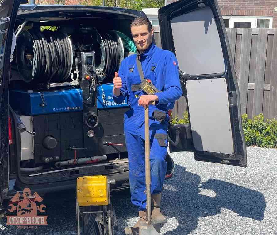 Een monteur bij de werkbus met grote hogedruk-slanghaspels, apparatuur voor hardnekkige afvoerverstoppingen in Boxtel