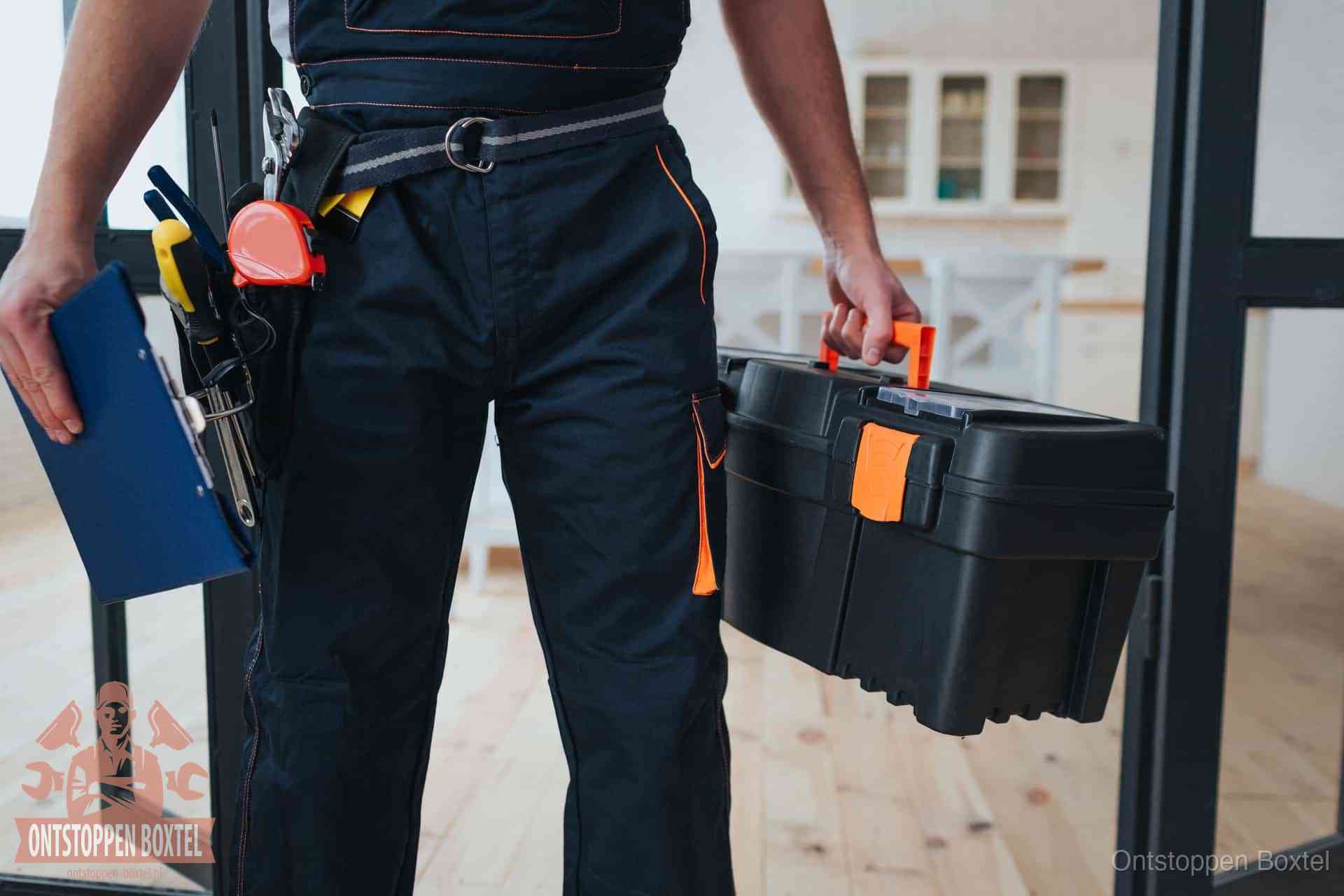 Een monteur met gereedschapsriem en klembord in een keuken, klaar om een transparante prijs voor het gootsteen ontstoppen in Boxtel te geven