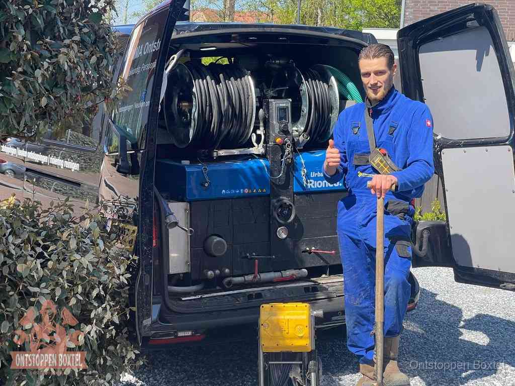 Lachende monteur bij de volle rioolreinigingsbus, een professioneel rioolontstoppingsbedrijf in Boxtel