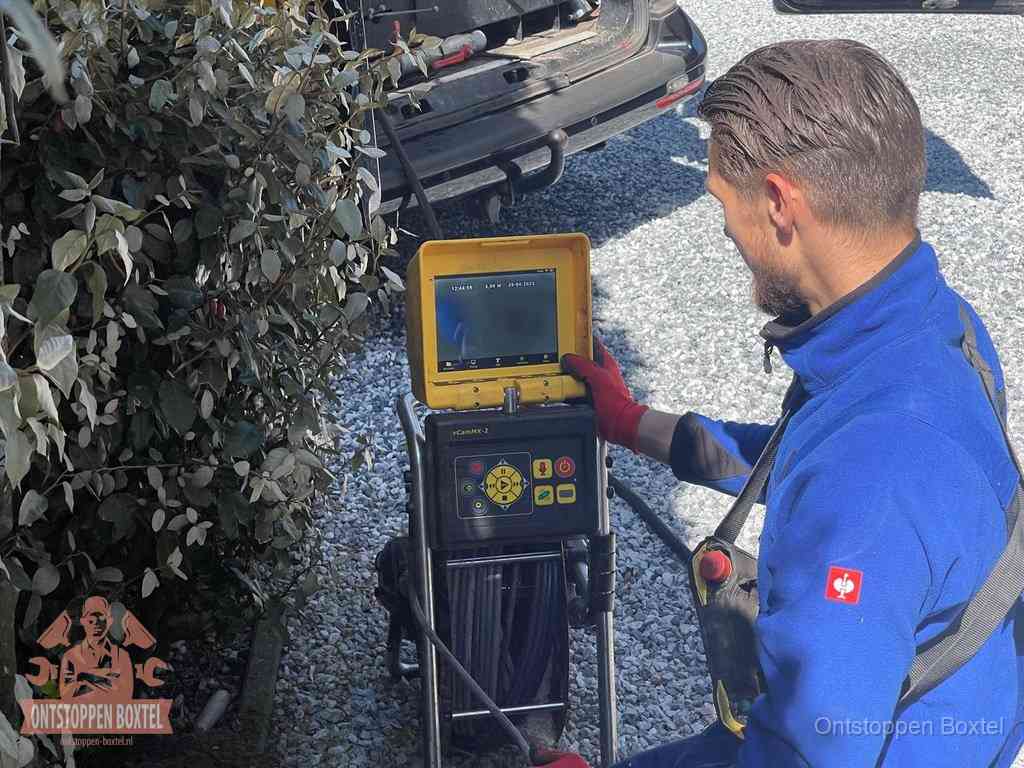Monteur bedient een rioolinspectiecamera met monitor voor rioolinspectie in Boxtel