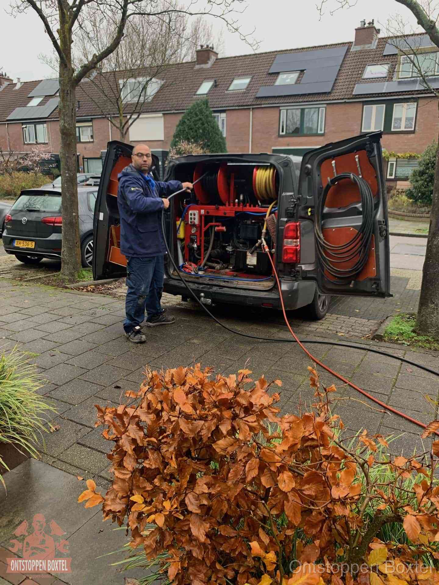 Monteur met rioolreinigingsbus levert rioolservice in de wijk in Boxtel