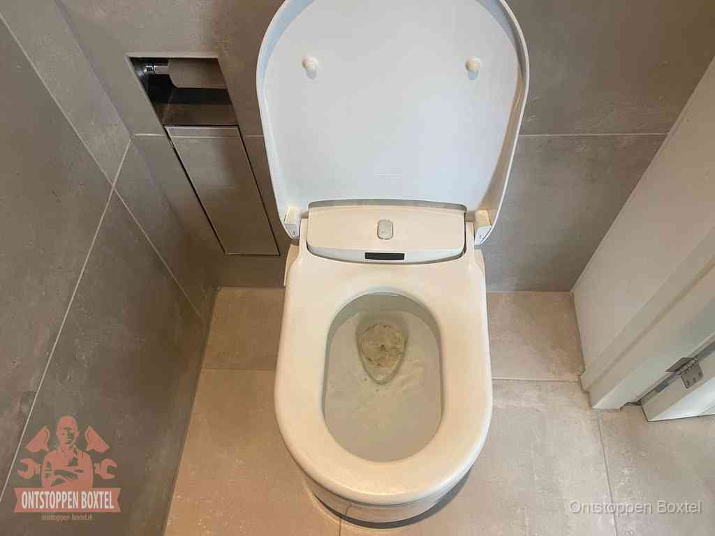 Een wit hangtoilet waarin een prop wc-papier op het water blijft drijven, een duidelijk signaal van een verstopte wc in Boxtel