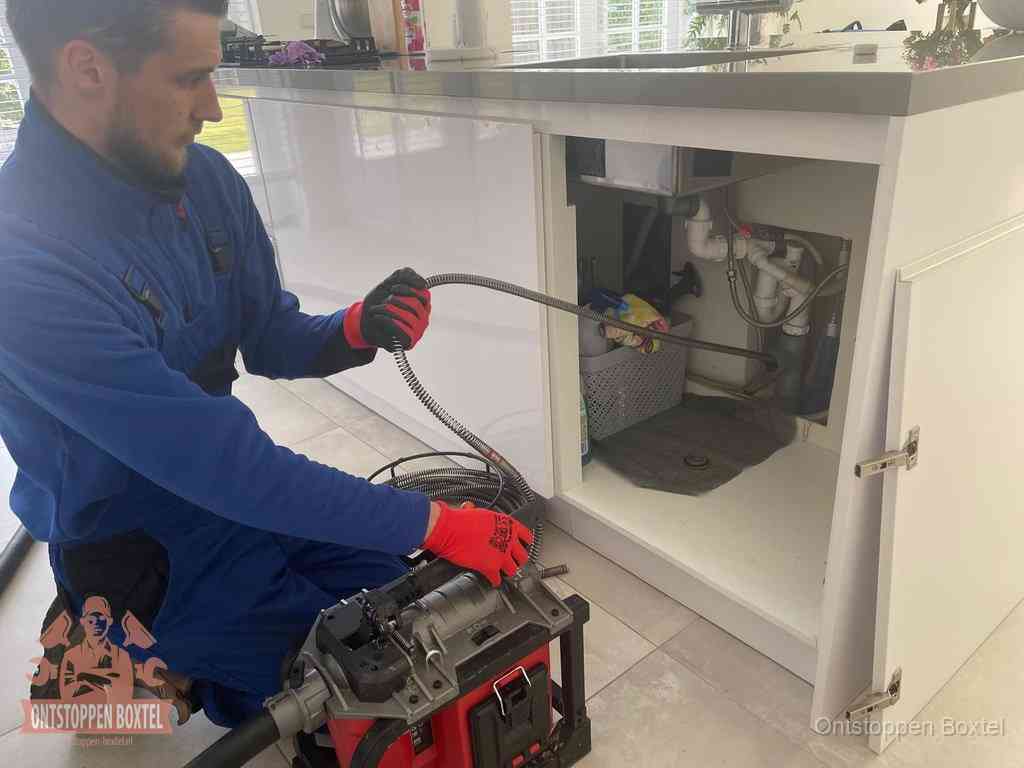 Een monteur reinigt de keukenafvoer grondig met een veermachine om terugkerende gootsteenverstoppingen te voorkomen in Boxtel