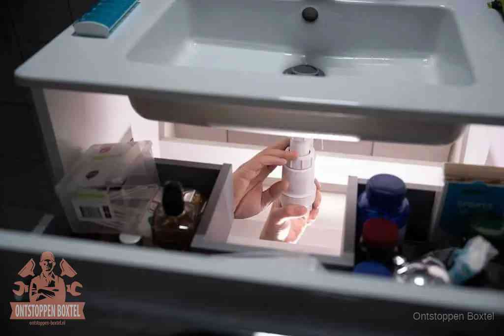 Een pompfles met zeep boven een wastafel in de toiletruimte, de warm water en afwasmiddel-methode om de wc te ontstoppen in Boxtel