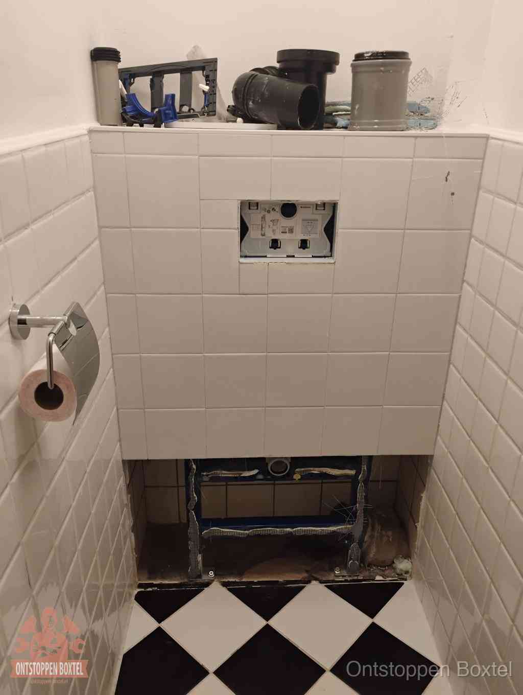 Een toiletruimte waar het hangtoilet en de inbouwreservoir-onderdelen zijn vrijgelegd voor onderhoud, periodiek nazicht voorkomt een wc-verstopping in Boxtel
