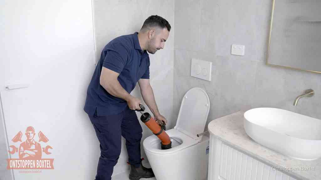 Een monteur gebruikt een handmatige perspomp (toiletontstopper) op een wandcloset tijdens het professioneel wc ontstoppen in Boxtel